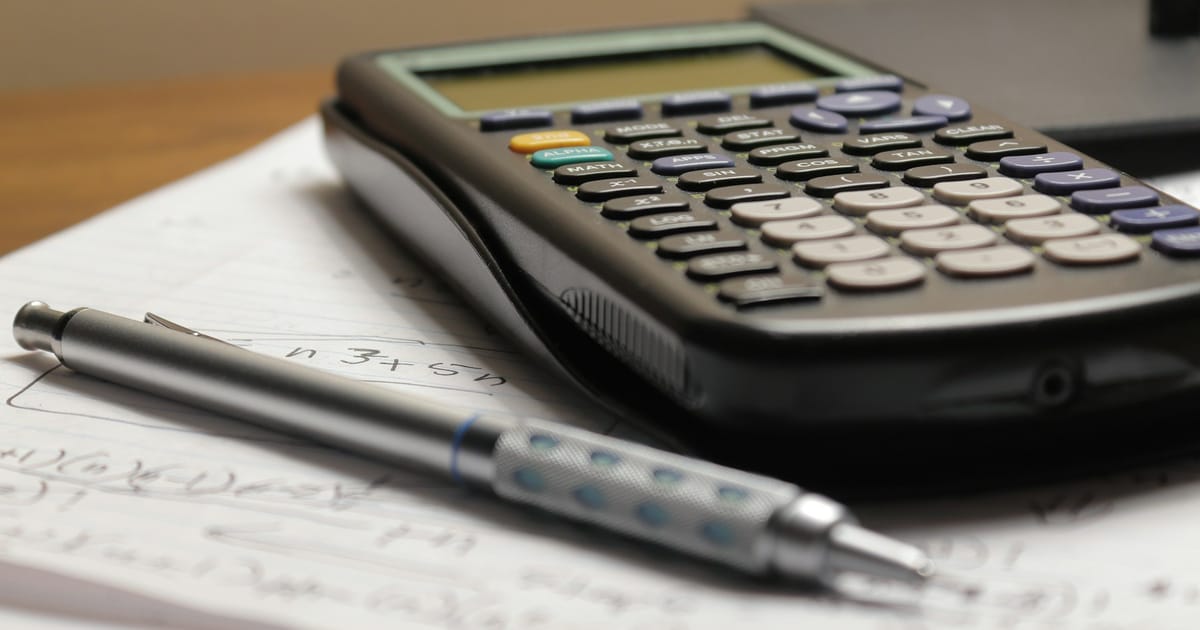 Una calculadora y un portaminas sobre una hoja con cuentas escritas a mano.