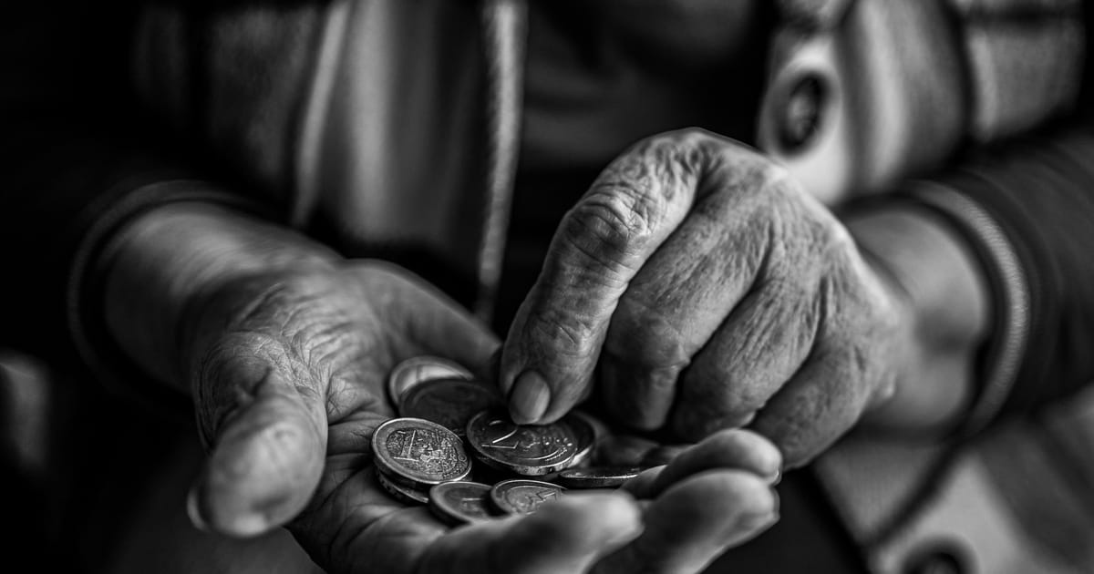 Las manos de una persona mayor sostienen unas monedas.