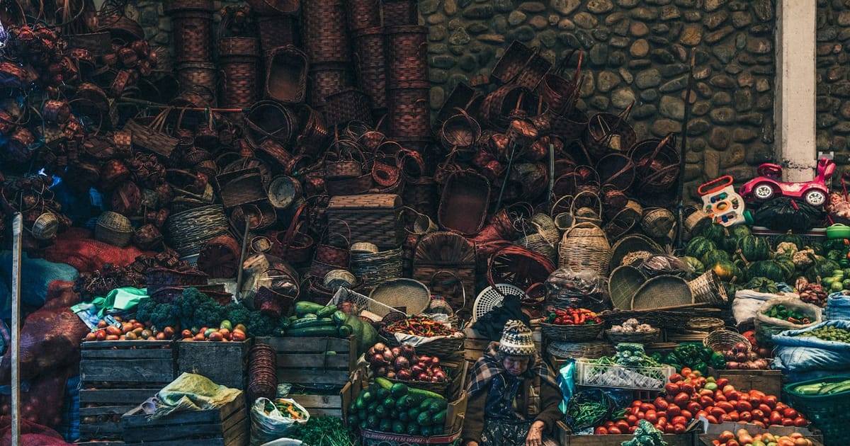 Un puesto de mercado en Sucre con cajas de verduras y canastas tejidas.