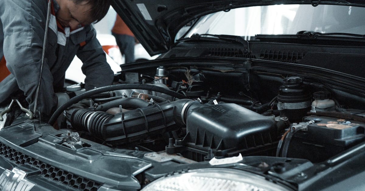 Un mecánico revisa el motor de un automóvil con el capó abierto.