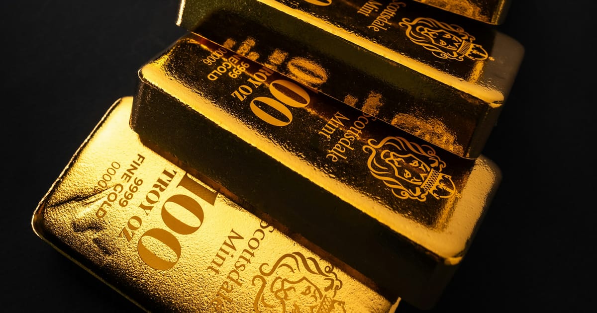 Lingotes de oro apilados sobre una superficie oscura.