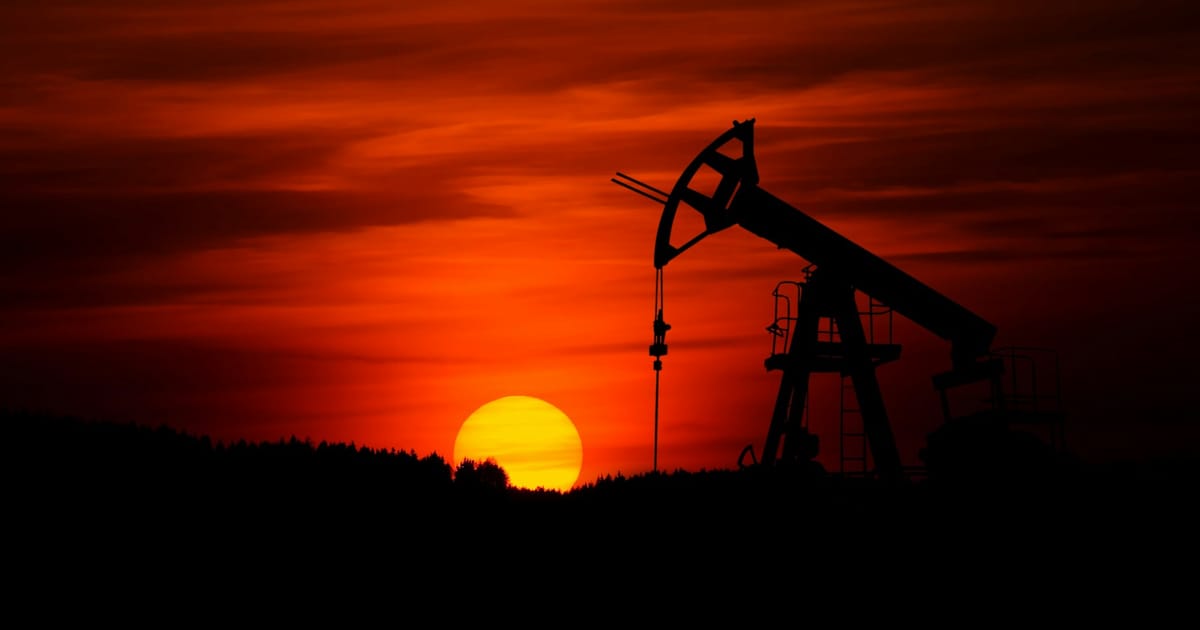 Una torre de extracción de petróleo recortada contra el cielo al atardecer.