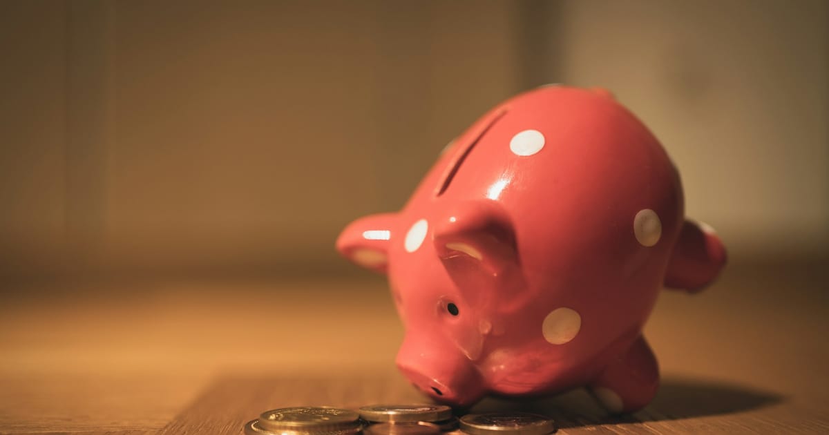 Una alcancía de cerámica en forma de chanchito junto a unas monedas.