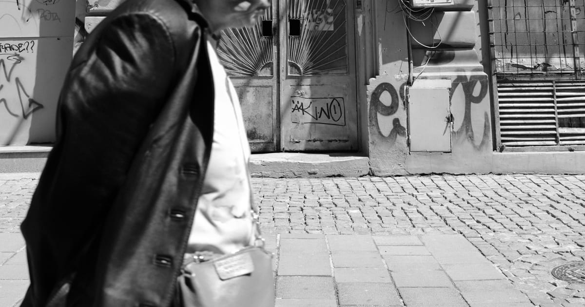 Una persona adulta mayor camina por una calle empedrada.